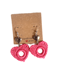 a pair of pink crochet heart earrings on a card