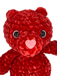 a red crocheted teddy bear on a black background