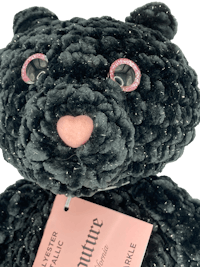 a black teddy bear with a pink tag on it