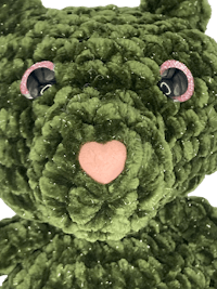 a green teddy bear with pink eyes