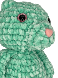 a green crocheted teddy bear with pink eyes