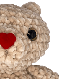 a crocheted teddy bear with a red nose