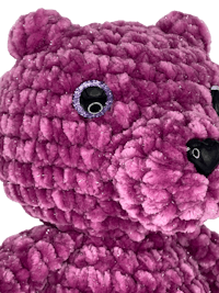 a purple teddy bear is shown against a black background