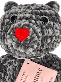 a gray teddy bear with a red heart tag