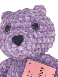 a purple teddy bear with a tag on it